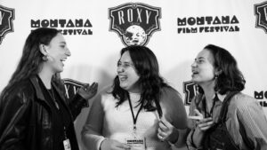 Three smiling women at a step and repeat.