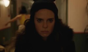 Image of a person with a black hat and dark coat looking forward.