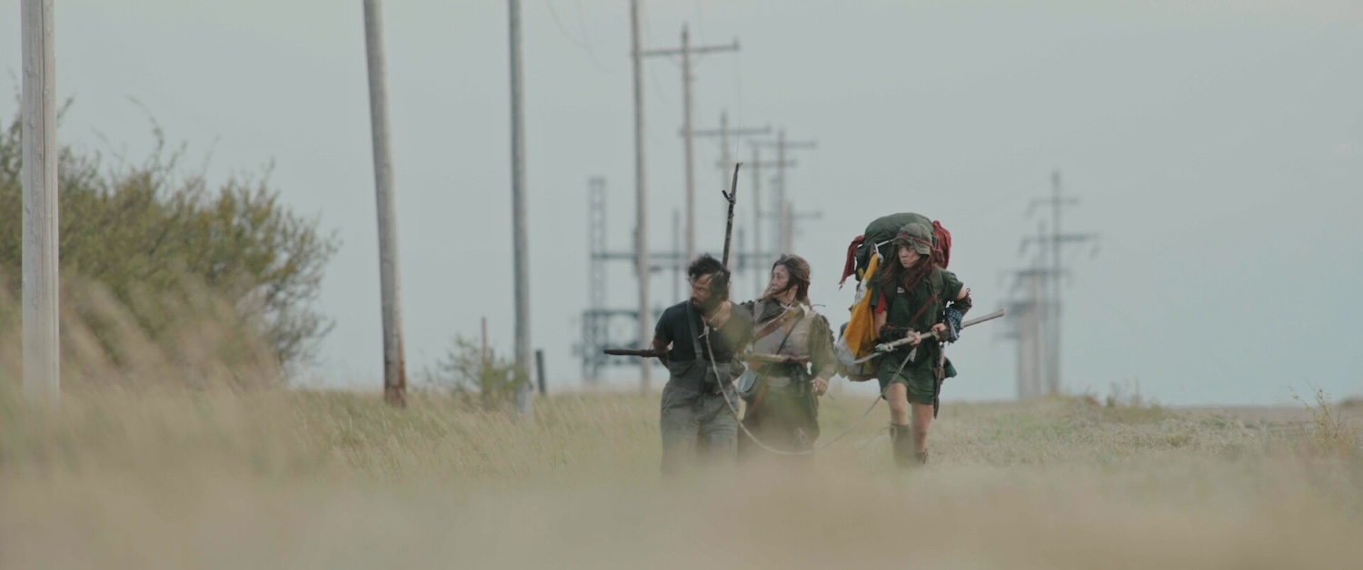 Image of three people with sticks and backpack walking.