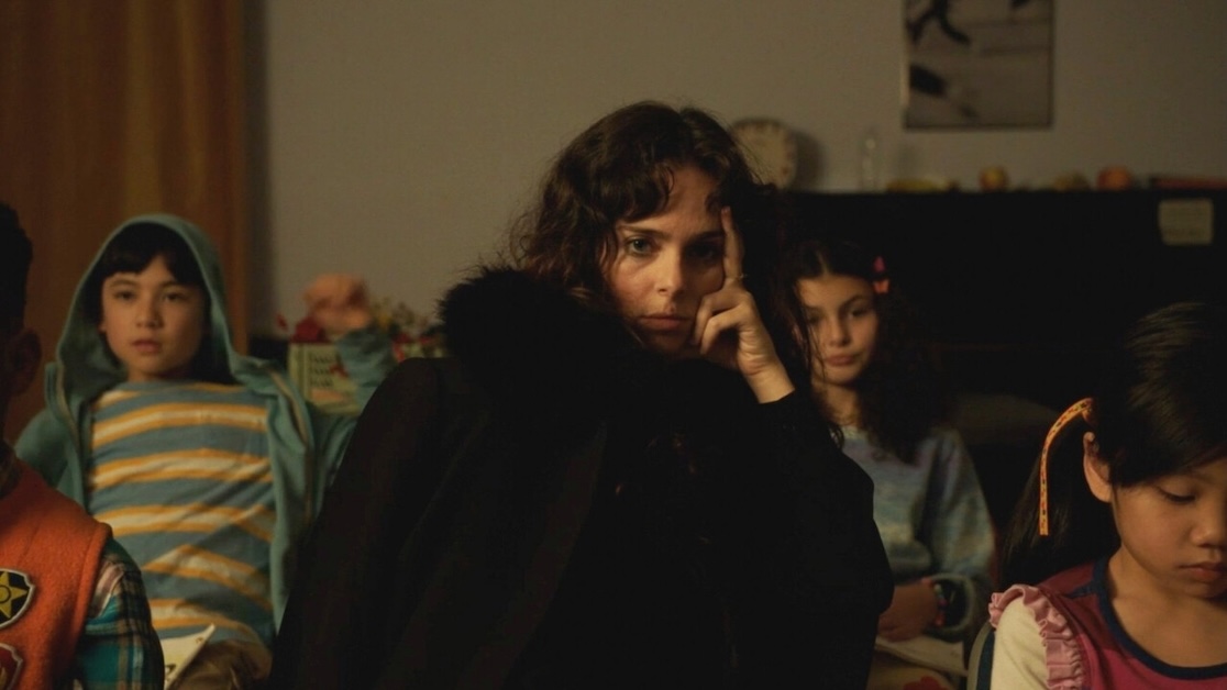 Image of a person in a big black coat looking toward camera.
