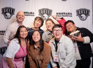 Image of group of people posing and smiling in front of stand and repeat.