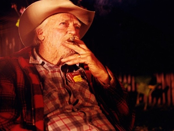 Image of a person with cowboy hat smoking a cigar.