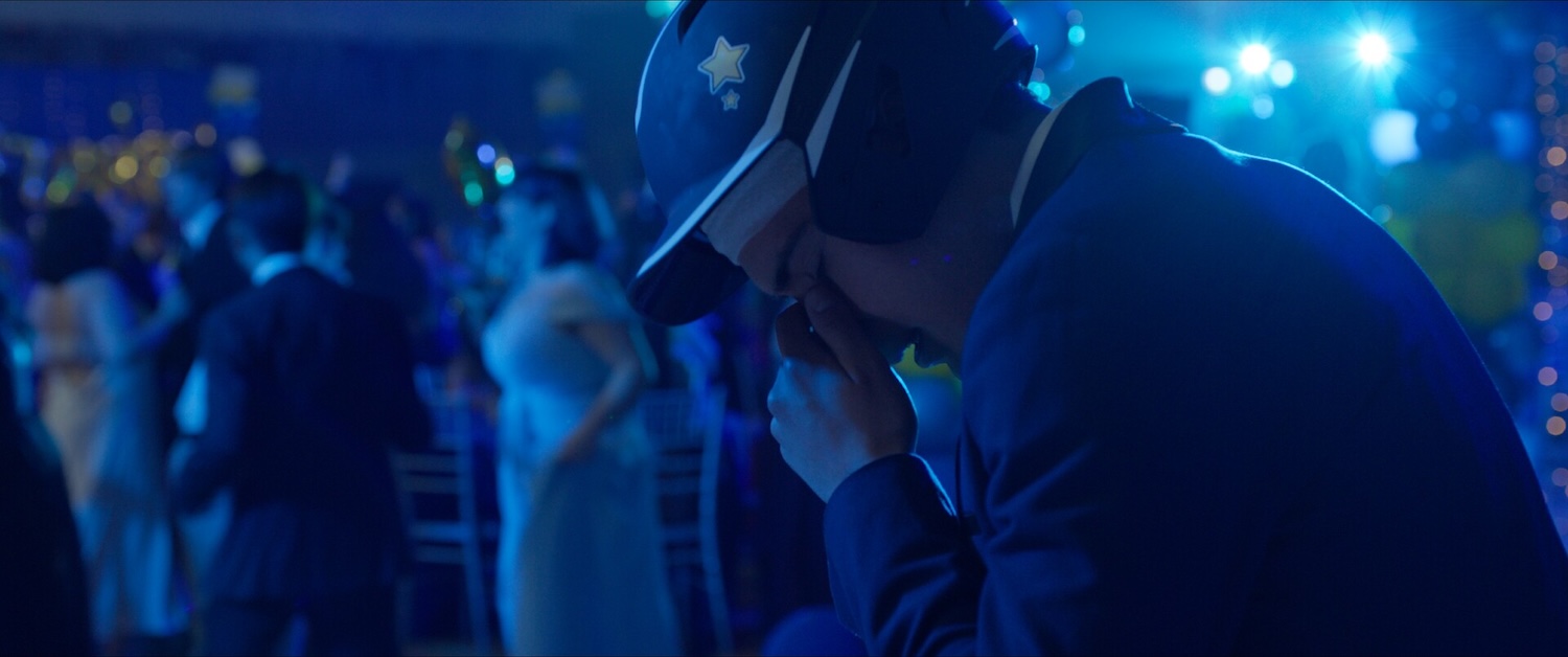 Image of person wearing helmet at a dance holding their nose between their eyes.