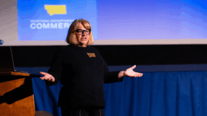 Image of person speaking in front of screen.