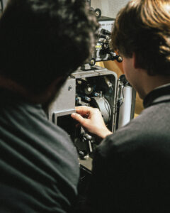 Two people looking at a movie projector.