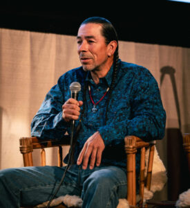 Person sitting with microphone.