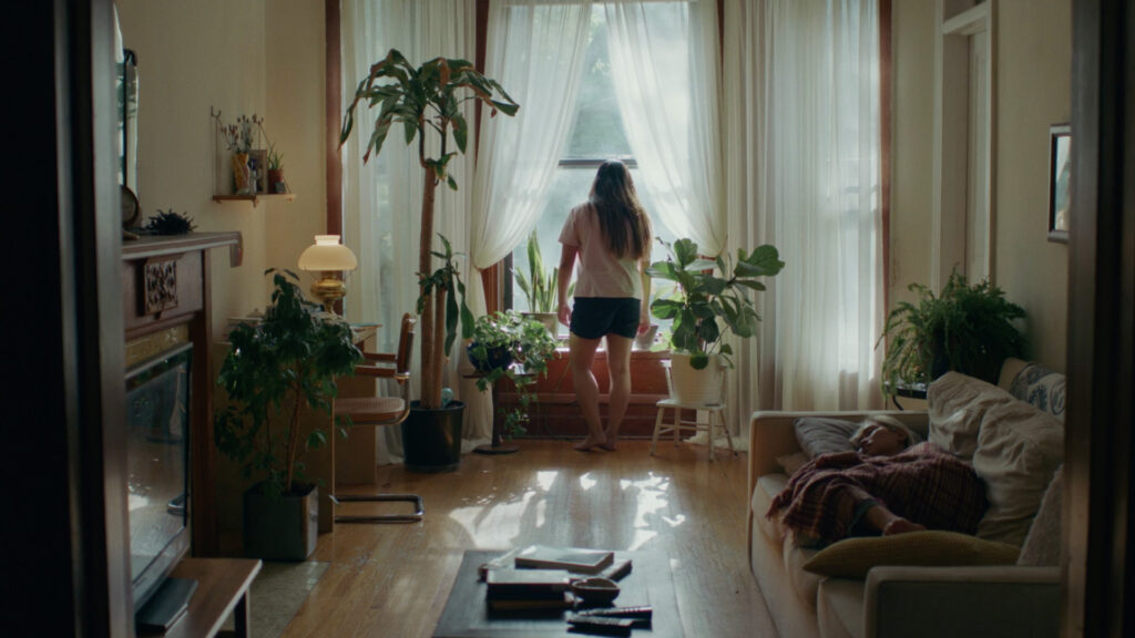Person looks out window in room with many houseplants