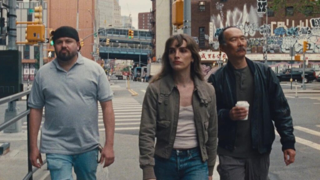 Three people walk down street in daytime.