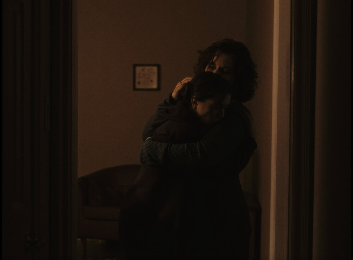Two people embrace in lowlight space