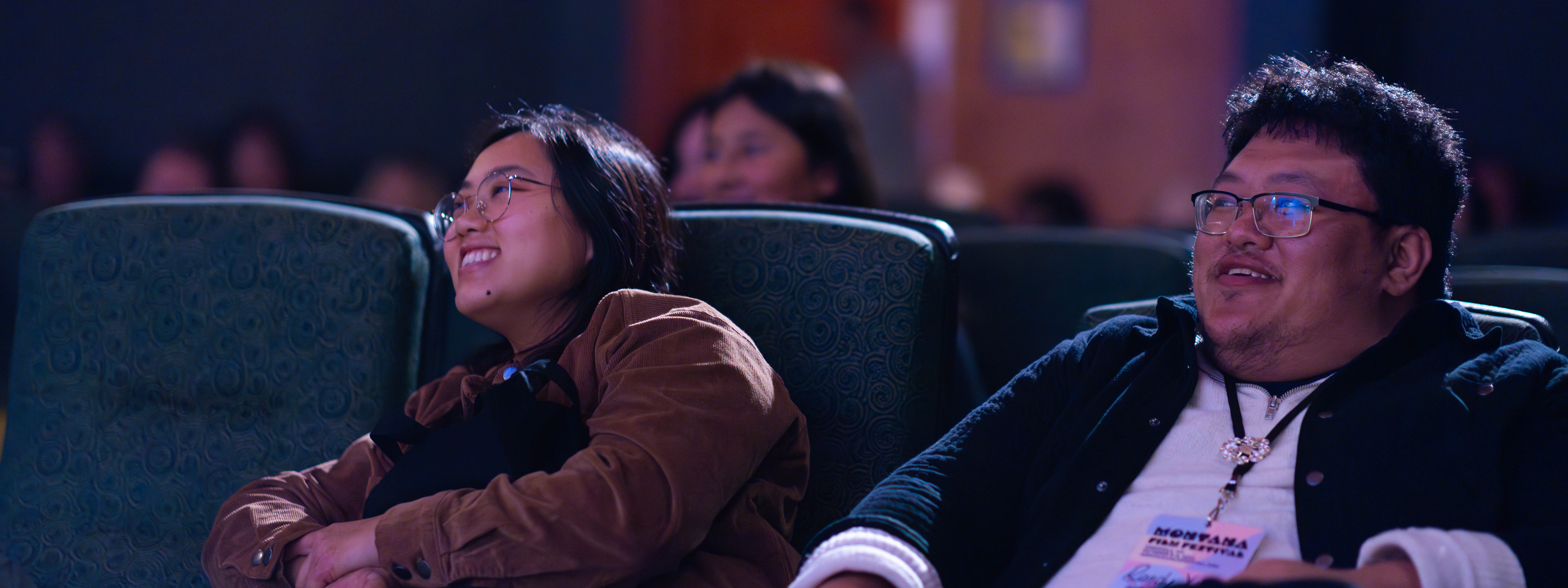 MTFF-DayTwo-37 Two people sit in theater looking up and smiling.