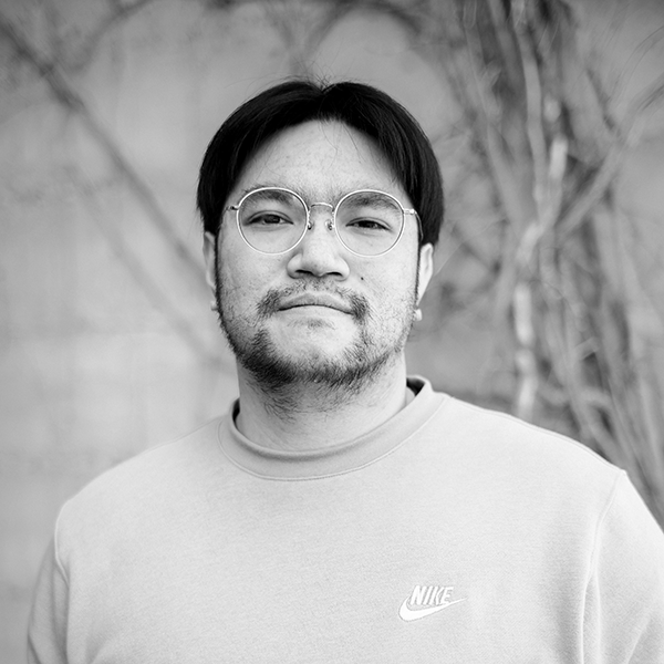 taira-headshot An image in black and white of a person with glasses looking towards camera.