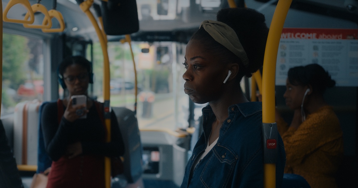 Image of person looking off in distance while riding bus with headphones in.