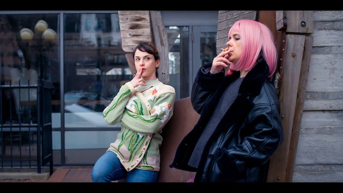The_Callback1 Image of two people standing outside smoking.
