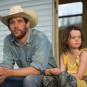 Image of person with cowboy hat and kid sitting down.