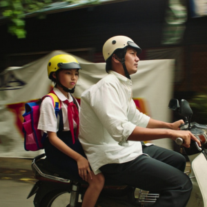 Image of an adult and kid on moped.