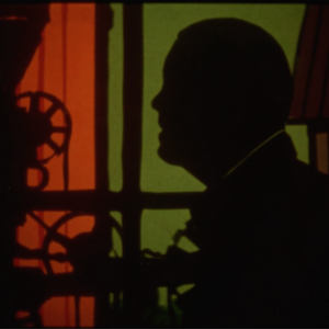 Image of shadow of a head in front of green and red background.