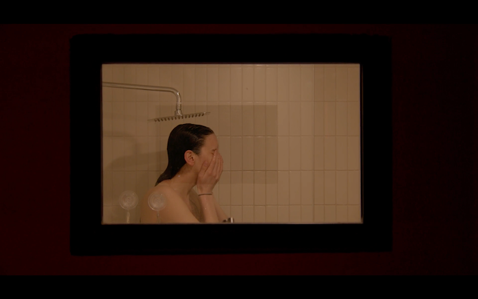 tb1 Image of a person in a shower holding their face.