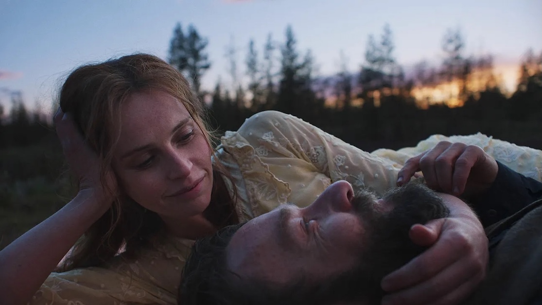 Image of two people laying down close together outside with sun on horizon.